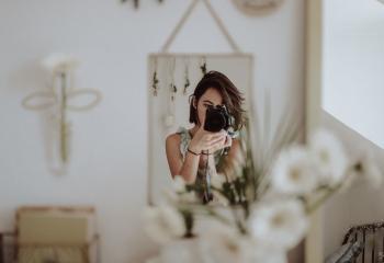 Woman looking through an SLR camera into a mirror